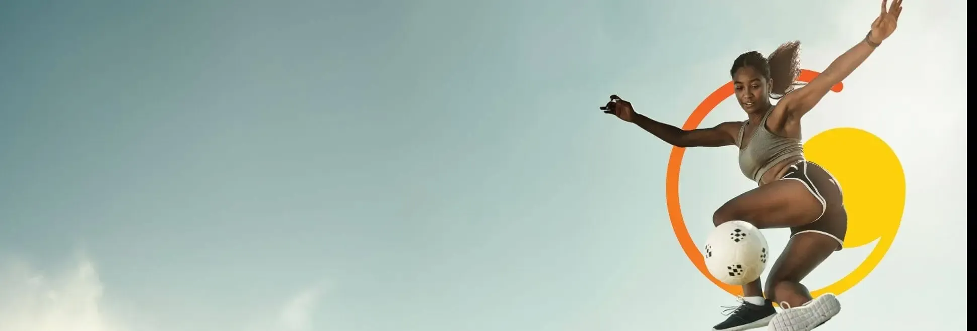 A person performing a mid-air soccer kick against a clear sky with colorful graphic elements behind them.