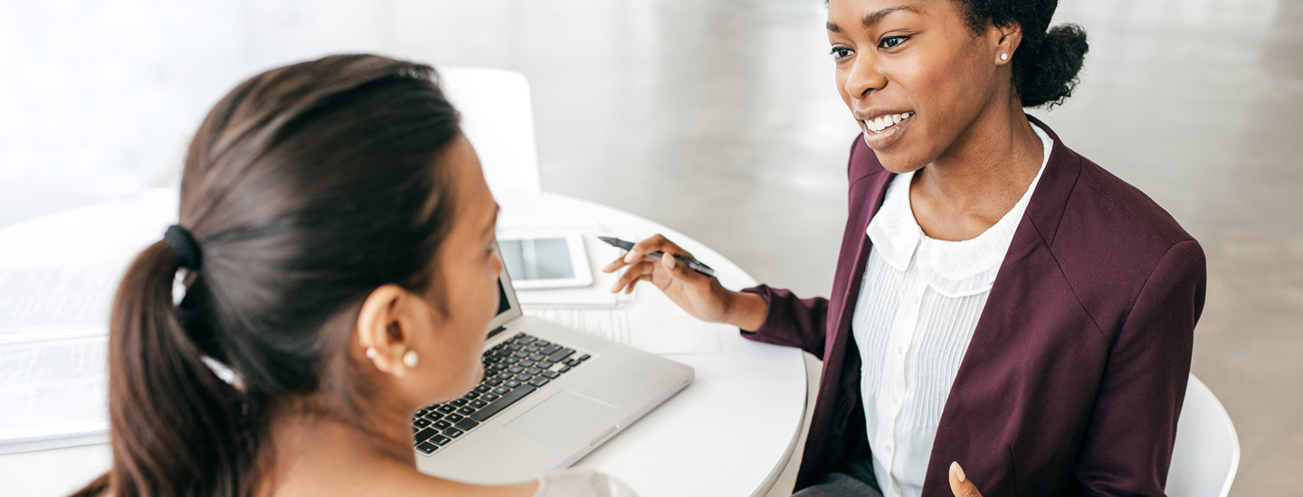 two woman talking and looking at a computer screen