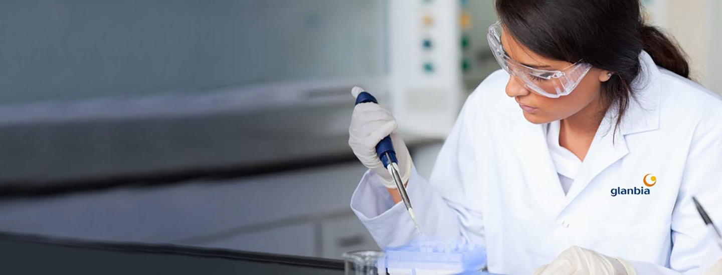 a woman in a white lab coat and lab glasses testing samples
