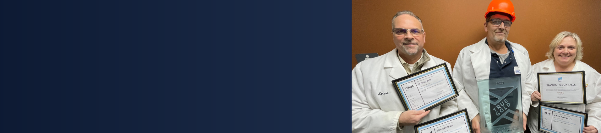 two men and a woman standing with certificates