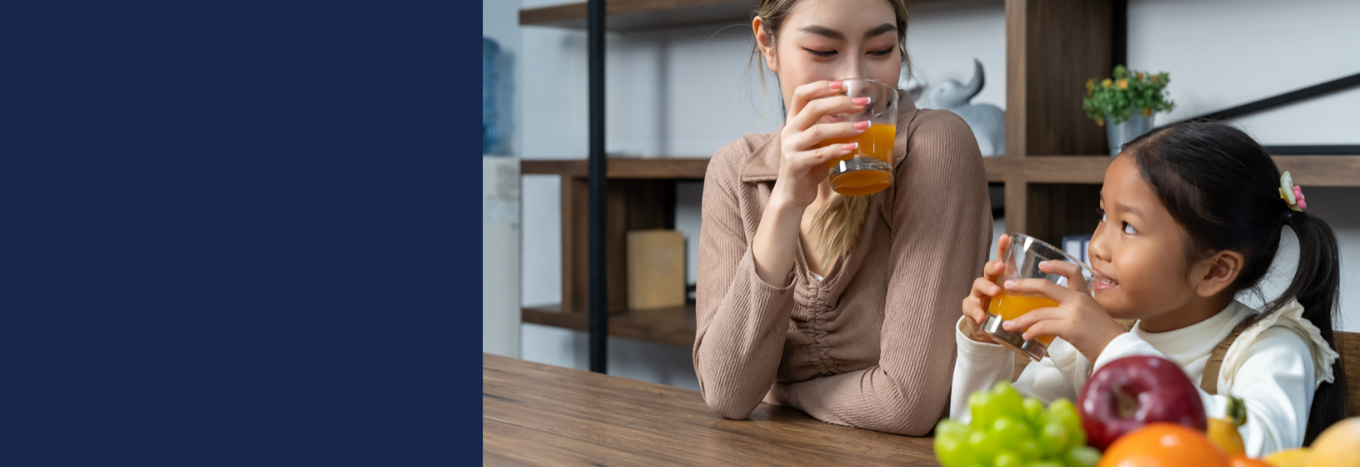 woman and girl sitting at a table drinking juice