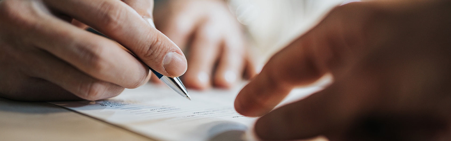 A person writing on a piece of paper signing a contract